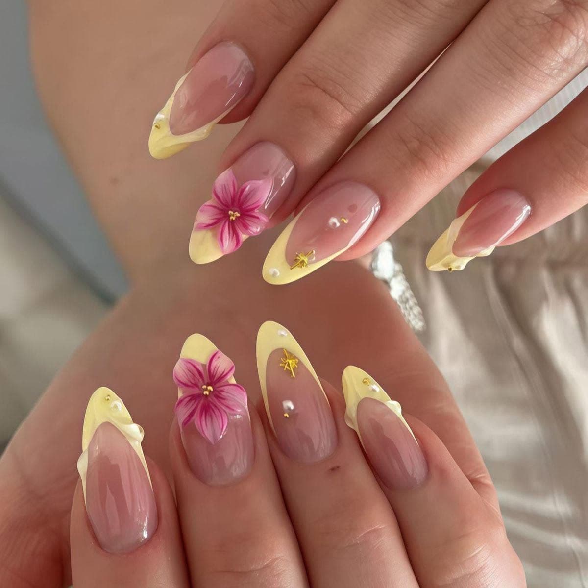 Yellow French tips with hand-painted pink flowers and gem accents